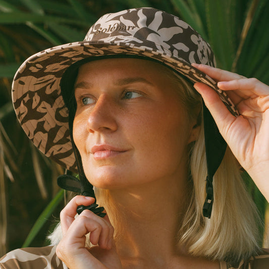 Woman wearing a chocolate brown patterned bucket hat with a blurred natural background